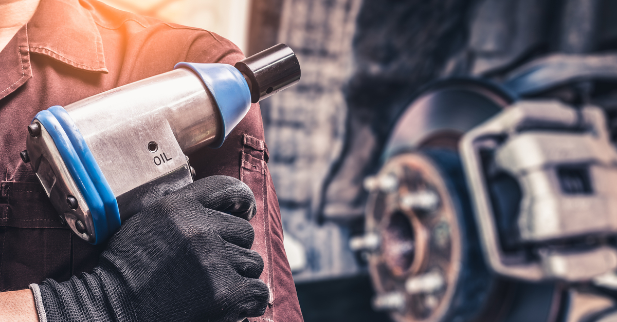 A person's hands are on the sides of a box against a chestnut brown background. The box has other shipping materials around it.