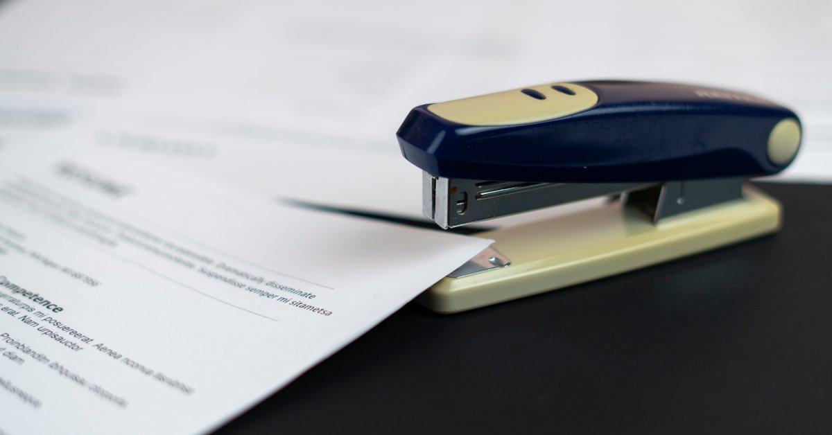 A sleek blue and white stapler rests on a smooth, black surface, neatly positioned over a document.